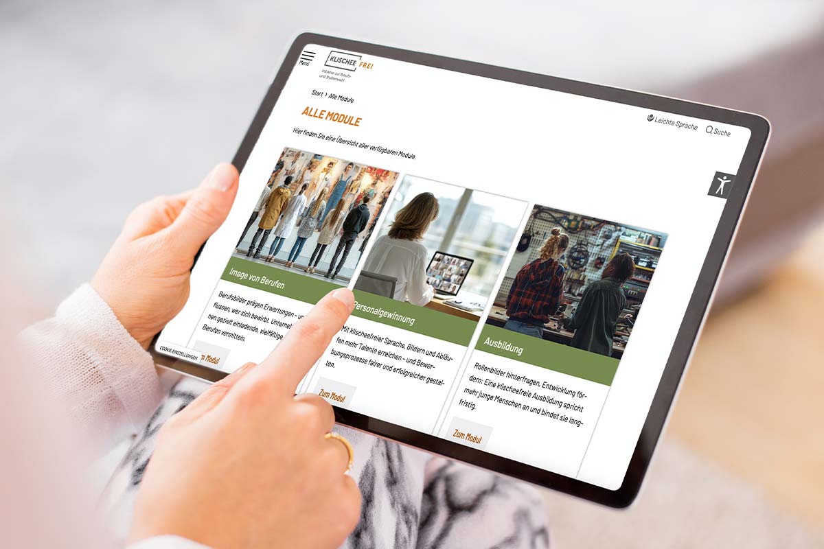 Eine Person hält ein Tablet in der Hand und surft auf der Kischeefrei E-Learning Plattform mit Bildungsmodulen, die auf dem Bildschirm angezeigt werden.