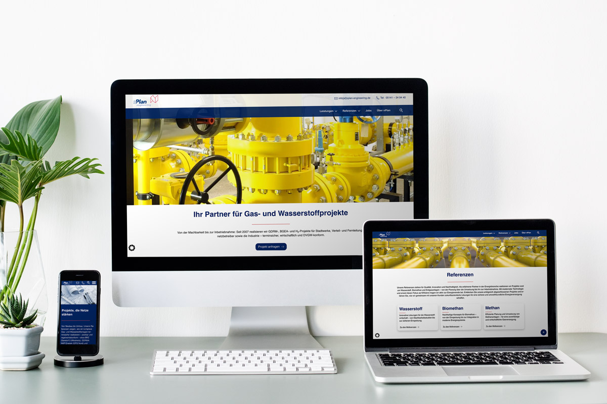 Schreibtisch mit Computer, Laptop und Telefon, auf dem die Website SKS über Gas- und Wasserstoffprojekte angezeigt wird; links eine Grünpflanze.