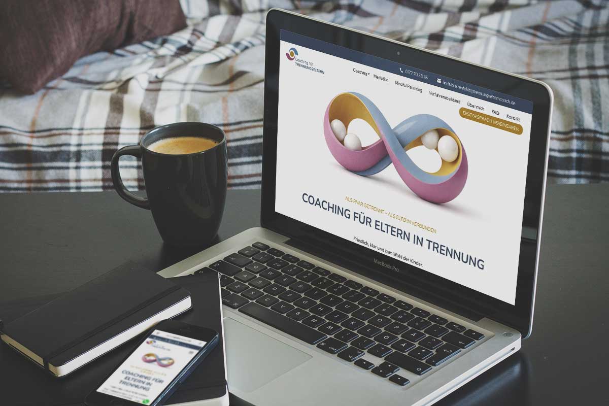 Ein Laptop auf einem Schreibtisch, auf dem eine Website zum Thema Elterncoaching zu sehen ist; daneben liegen ein Handy, ein Notizbuch und eine Kaffeetasse.